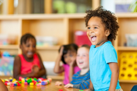 Young children engaging in hands-on learning activities in a bright, welcoming classroom environment featuring educational materials and toys, conveying a warm and nurturing atmosphere.